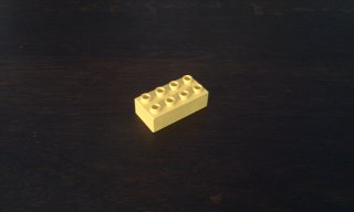 DUPLO brick on dark wooden table, at some distance